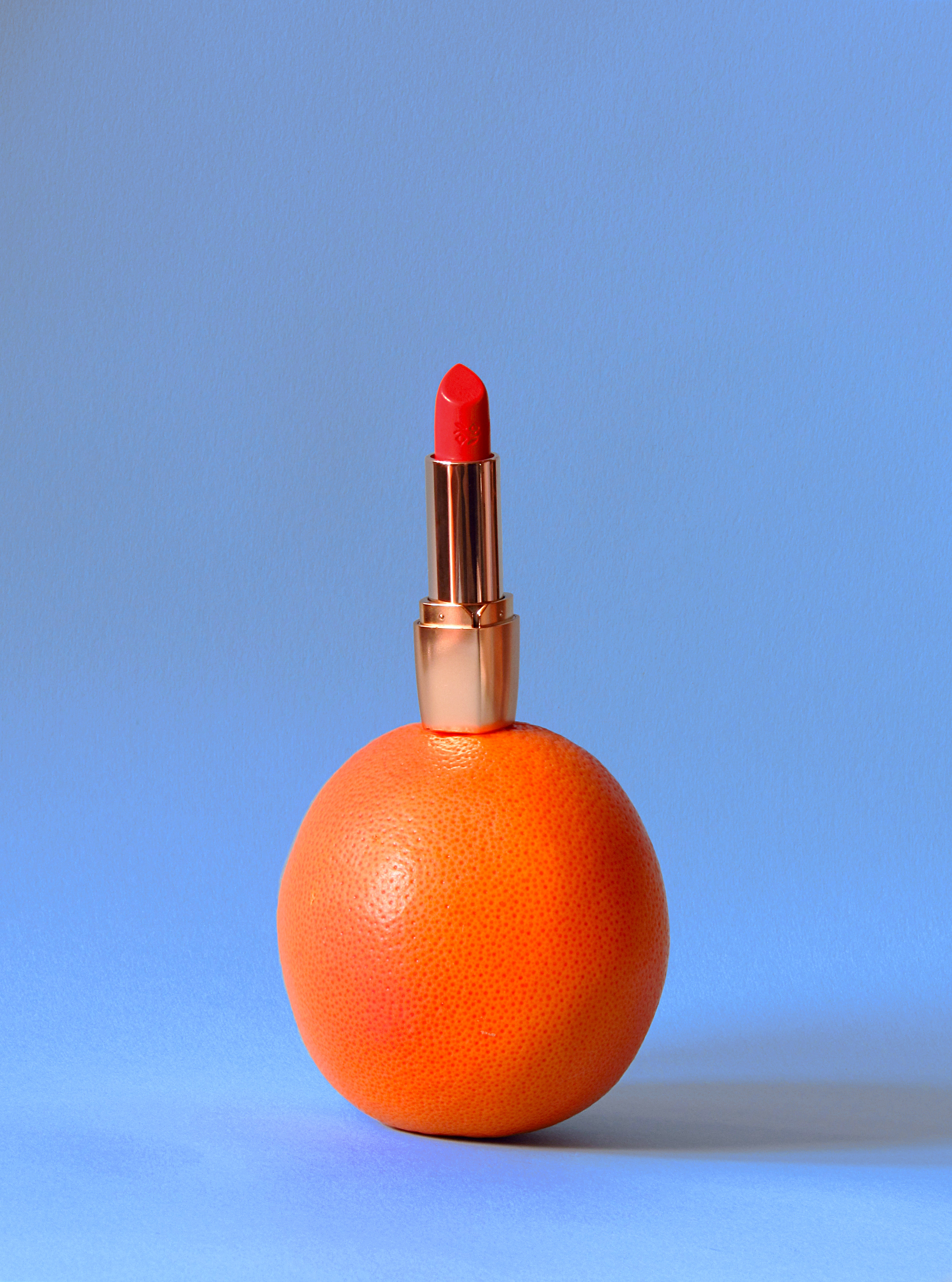 Deborah Milano Rossetto Milano Red Lipstick in No. 11 standing on a grapefruit for color comparison.