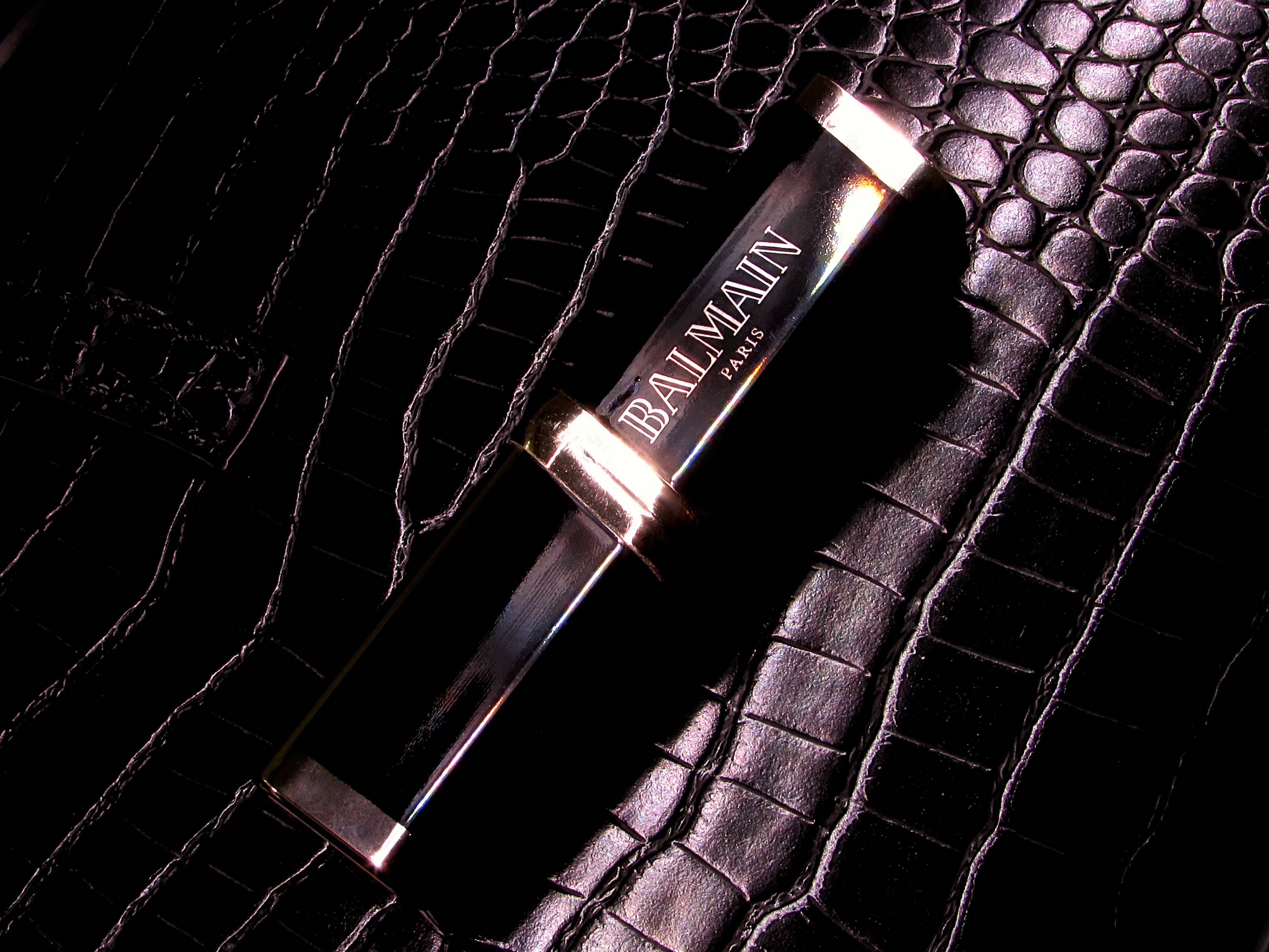 L’Oréal Paris x Balmain Color Riche limited edition purple lipstick in 468 Liberation on a black leather purse.