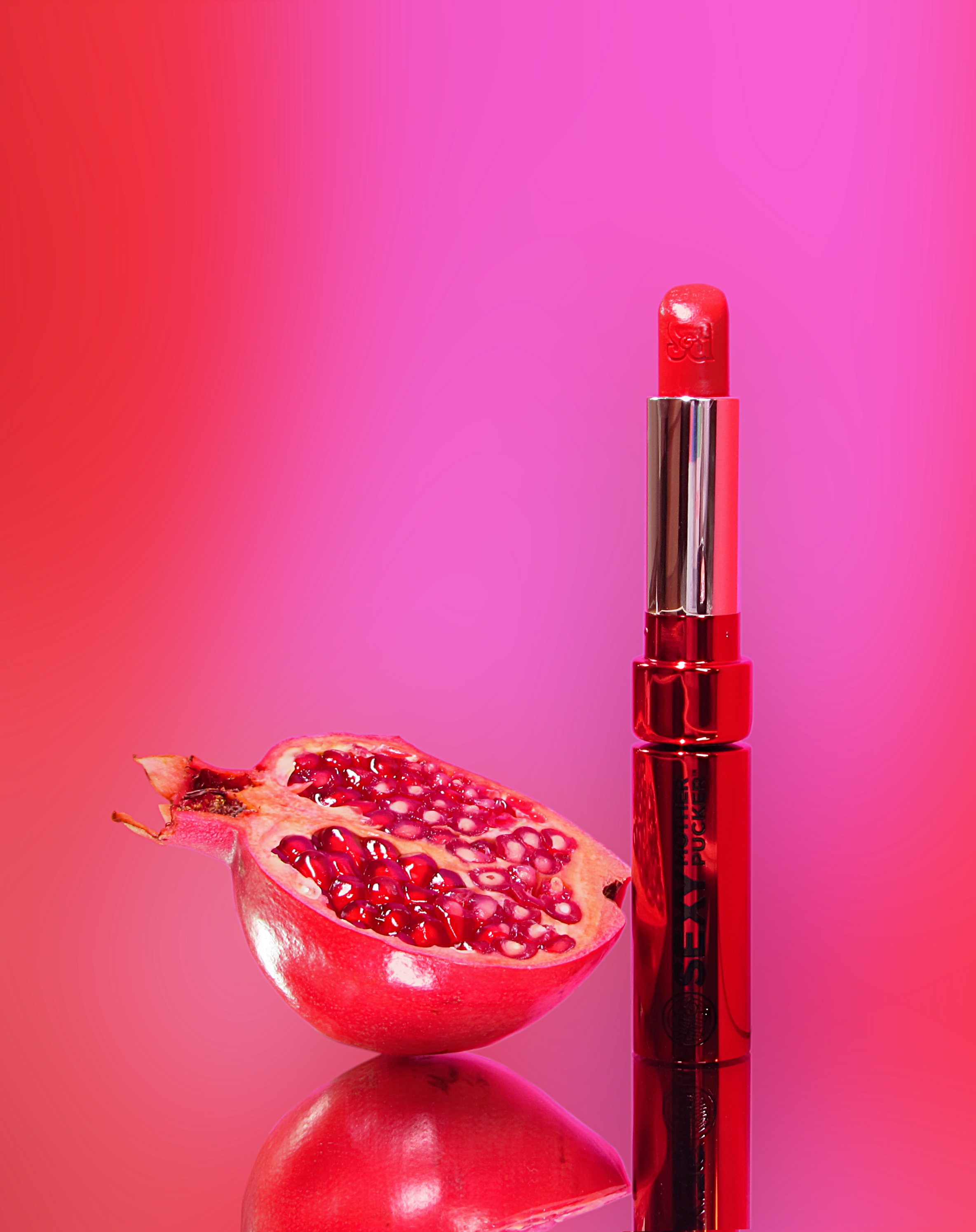 Soap & Glory Sexy Mother Pucker in Poppy Power next to a pomegranate.